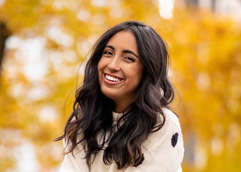 Lissette Calviero smiling with a yellow background.